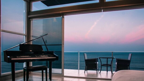 Una habitación con un piano, dos sillas y una cama.