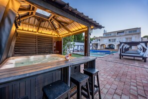A hot tub area with a wooden deck, a covered seating area, and a pool in the background. - Villa Cristallo - Ten Bedroom Villa, Sleeps 20 (Praia da Luz)
