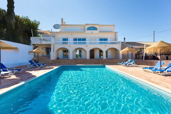A swimming pool with lounge chairs and a building with a balcony. - Villa Cristallo - Ten Bedroom Villa, Sleeps 20 (Praia da Luz)