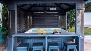 A covered outdoor bar area with a hot tub, two stools, and a table with drinks and fruit. - Villa Cristallo - Ten Bedroom Villa, Sleeps 20 (Praia da Luz)