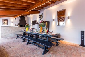 A dining area with a brick wall, wooden beams, and a table set for a meal. - Villa Cristallo - Ten Bedroom Villa, Sleeps 20 (Praia da Luz)