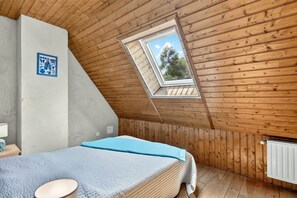 A bedroom with a sloped ceiling, a skylight, a bed with a blue blanket, a bedside table, and a radiator. - Robin - Four Bedroom Villa, Sleeps 6 (Sainte-Alvère)