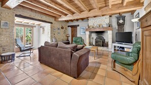 Ein gemütliches Wohnzimmer mit Kamin, Ledersofas, einem Fernseher und einer Steinwand.