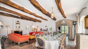 A dining area with a long table set for a meal, wooden beams on the ceiling, and a fireplace.