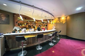 A bar area with a counter, stools, and a red carpet. - Galaxy Hotel Banjarmasin (Banjarmasin)