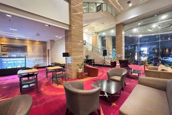 A hotel lobby with a red carpet, seating area, and a staircase leading to an upper level. - Galaxy Hotel Banjarmasin (Banjarmasin)