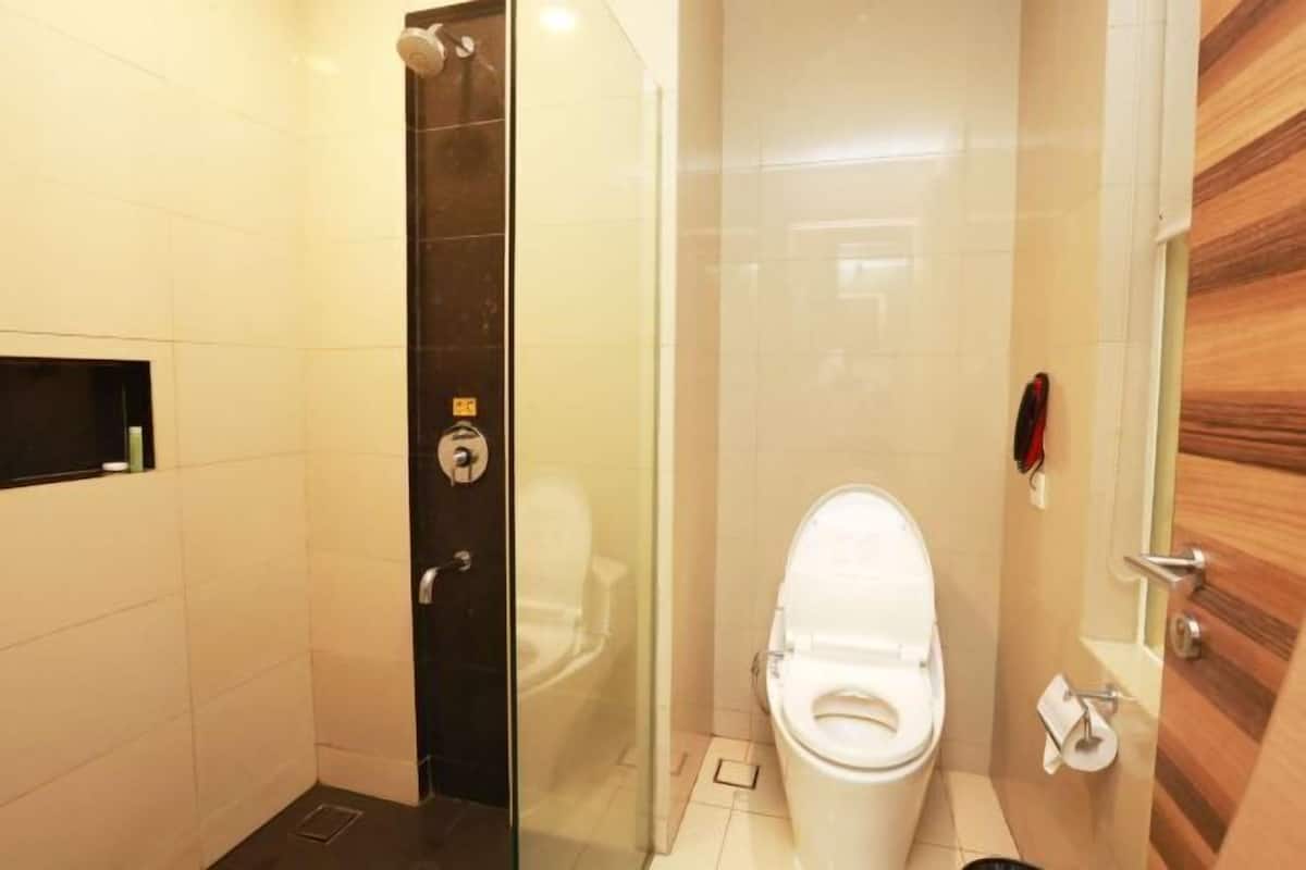 A small, modern bathroom with a glass shower enclosure, a white toilet, and a wooden door.