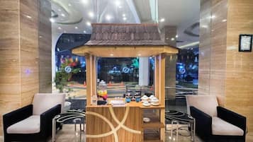 Un área de recepción con un pequeño quiosco, dos sillones y un diseño de techo moderno.