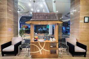 Un área de recepción con un pequeño quiosco, dos sillones y un diseño de techo moderno.