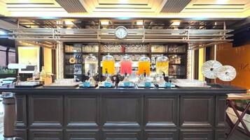 Zona de bar con mostrador oscuro, varios dispensadores de bebidas y un reloj en la pared.