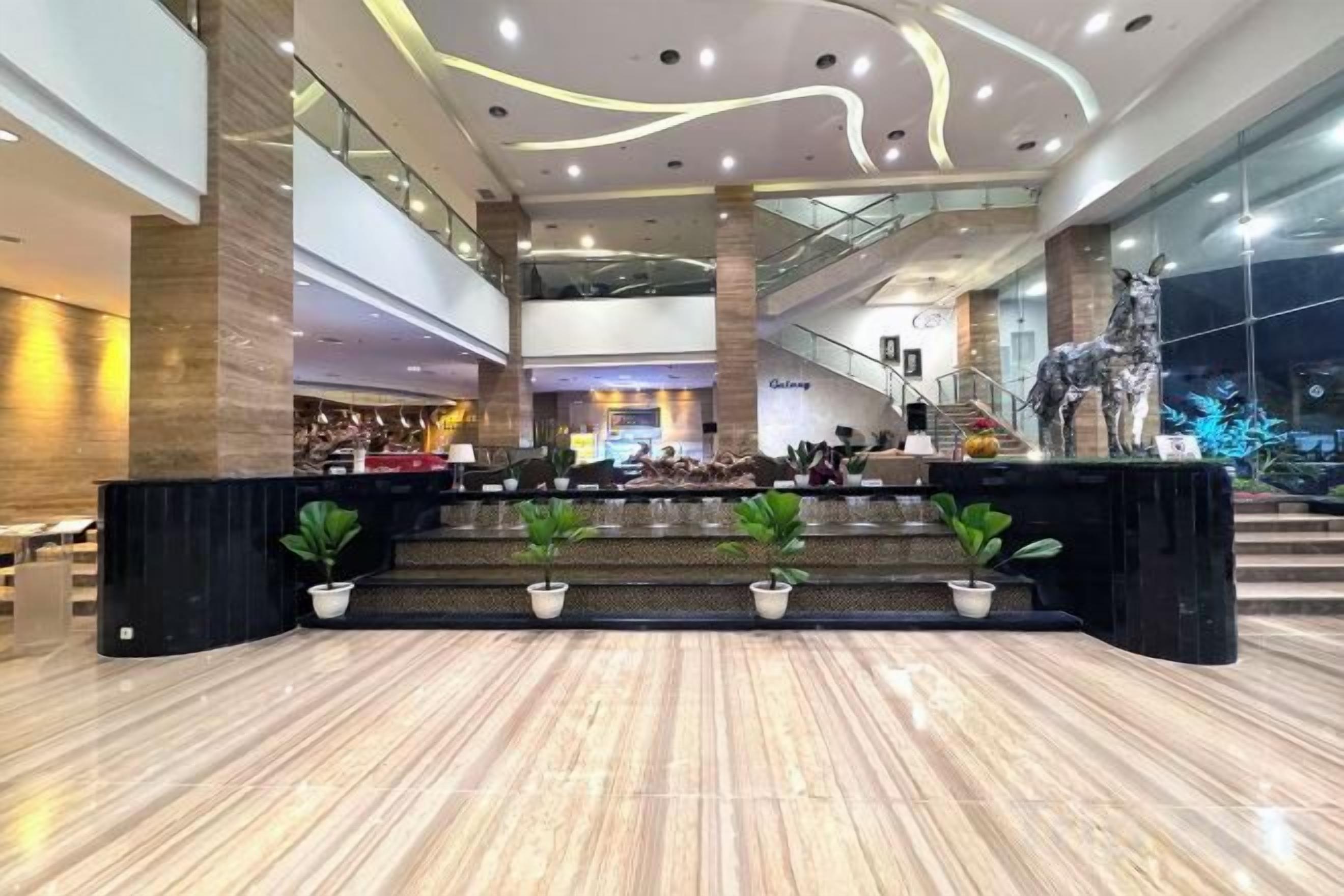 A spacious lobby with a reception desk, seating area, and a staircase leading to upper floors.