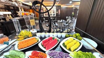 Un bufé con diversos alimentos, incluyendo frutas, verduras y tazones de sopa.