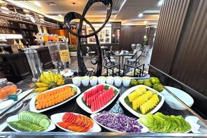 Un bufé con diversos alimentos, incluyendo frutas, verduras y tazones de sopa.