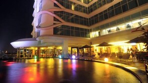 Un hotel moderno con area piscina, posti a sedere all'aperto e un ingresso ben illuminato.