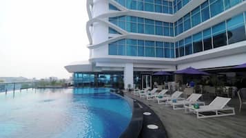 Um hotel moderno com piscina, espreguiçadeiras e vista para a cidade.