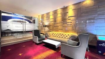Un moderno vestíbulo de hotel con un sofá, sillones, una mesa de centro y una alfombra roja con motivos de estrellas.