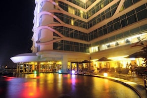 A multi-story hotel with a pool area, outdoor seating, and a modern architectural design. - Galaxy Hotel Banjarmasin (Banjarmasin)