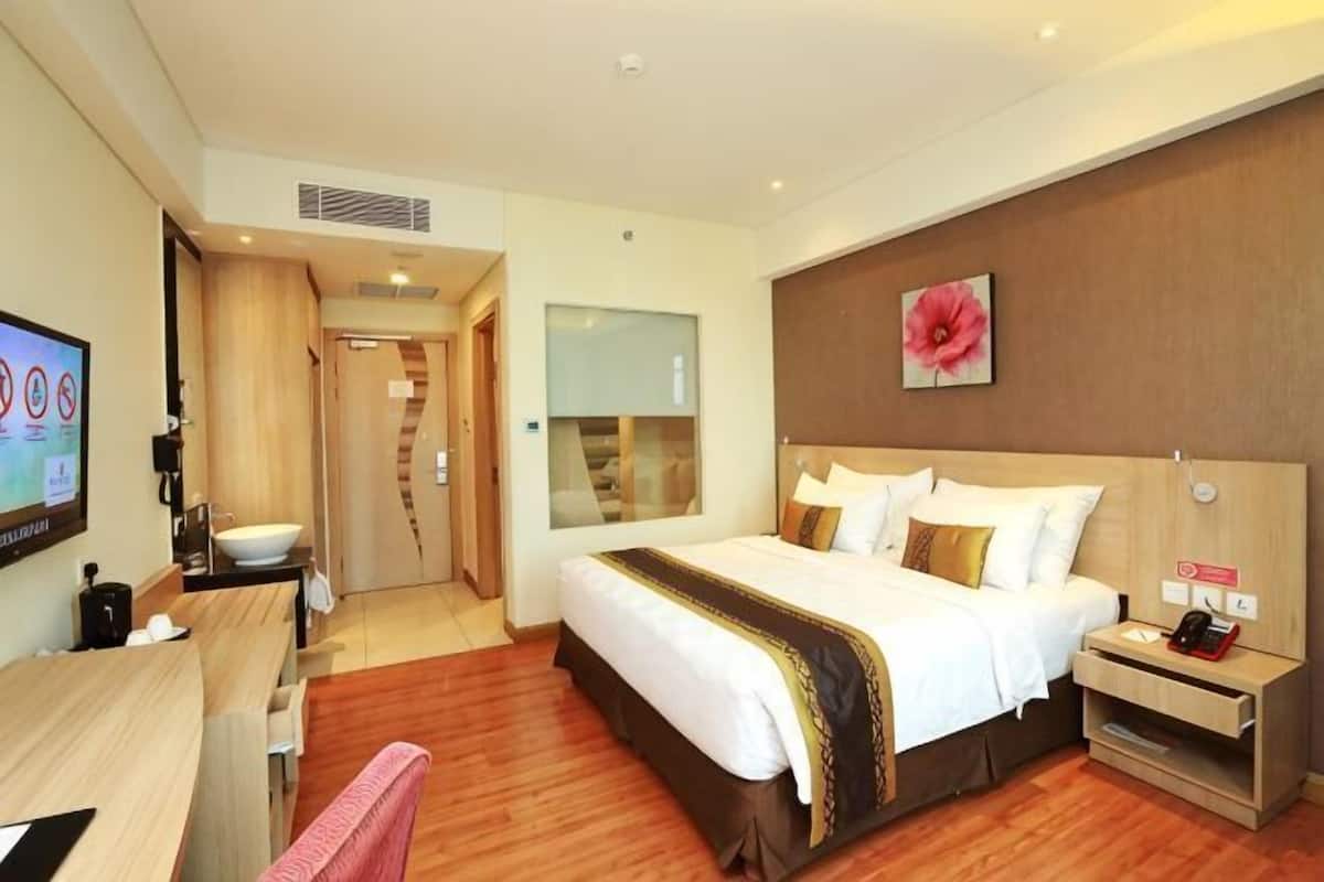 A hotel room with a large bed, bedside table, and a TV.