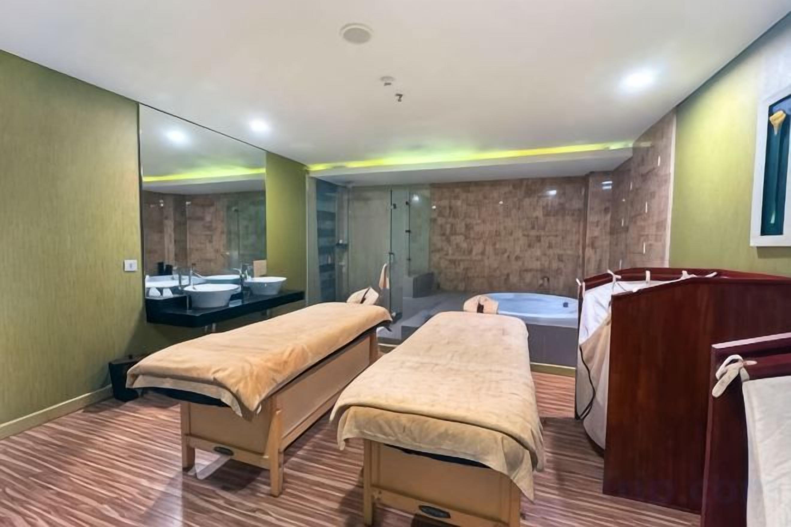 Habitación de hotel con dos camas, un espejo grande, una bañera y zona de ducha.