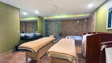 Habitación de hotel con dos camas, un espejo grande, una bañera y zona de ducha.
