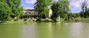 A building with a tiled roof, surrounded by a body of water and greenery.