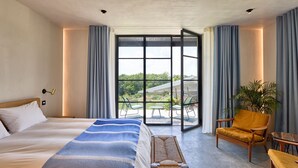A hotel room with a large bed, a wooden bench, a yellow armchair, a small table, and a potted plant. - Le Grand Chene - Five Bedroom Villa, Sleeps 10 (Touffailles)