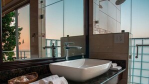 Une salle de bain moderne dotée d’un grand lavabo sur pied, d’une douche à parois de verre et offrant une vue sur l’extérieur.