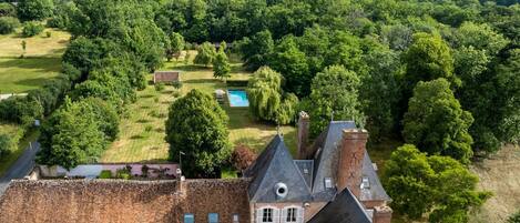A large estate with a main building, a swimming pool, and extensive greenery.