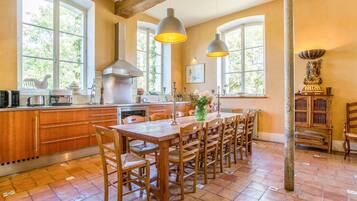 Een keuken met houten kasten, een centraal eiland, hanglampen en uitzicht op groen buiten.