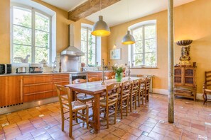 A kitchen with wooden cabinets, a central island, pendant lighting, and a view of greenery outside. - Chateau Seiguier - Six Bedroom Castle, Sleeps 12 (Brinon-sur-Sauldre)