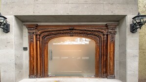 A building entrance with a glass door, flanked by ornate wooden carvings and two wall-mounted lanterns. - Collection O Lavanda Anzures Mexico City (Mexico City)