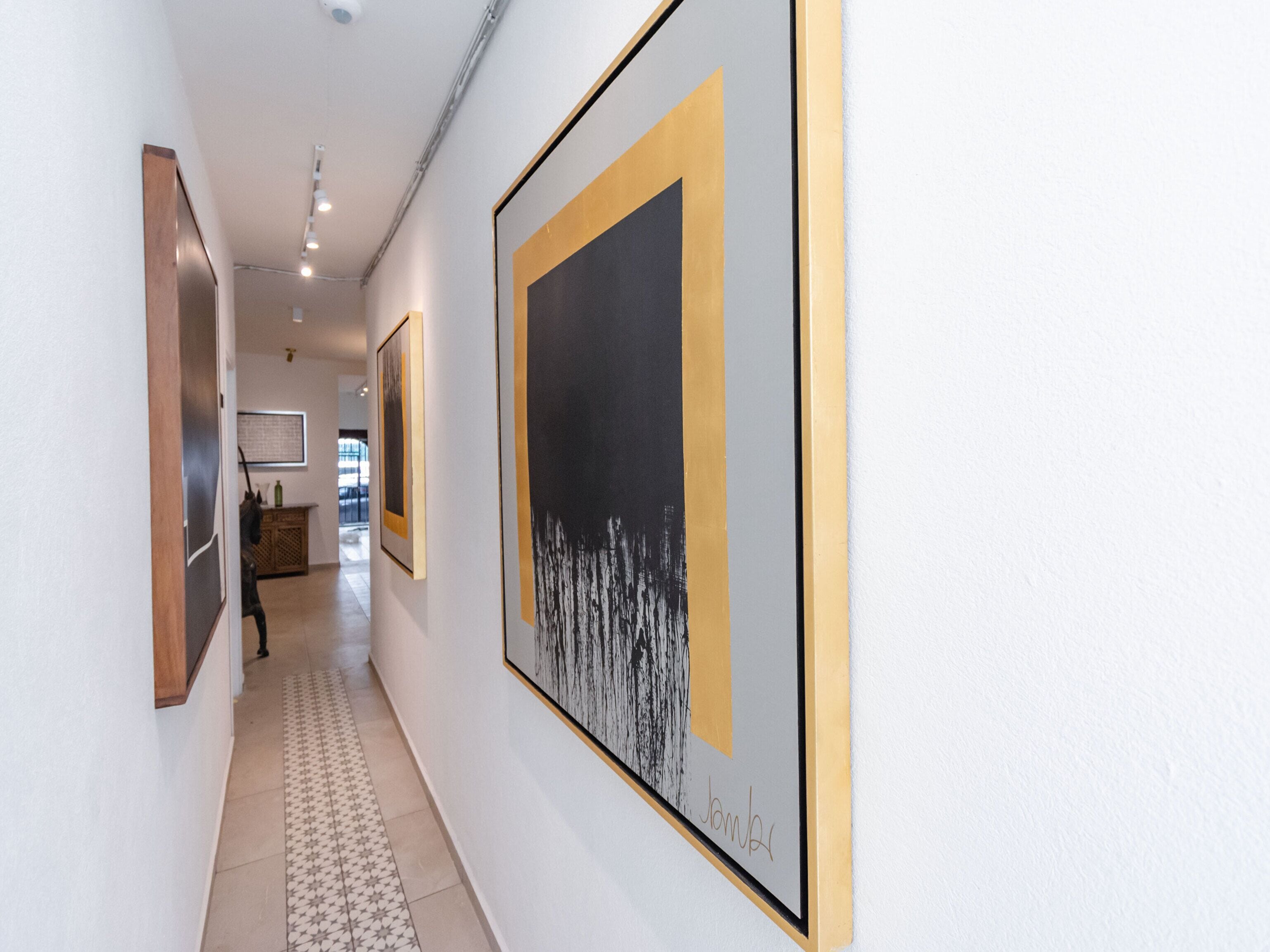 A hallway with framed artworks on the walls and a patterned floor.