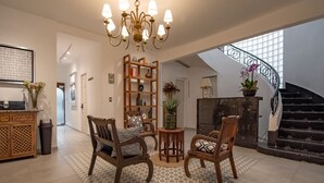 A spacious living area with a chandelier, wooden chairs, a bookshelf, and a staircase. - Collection O Lavanda Anzures Mexico City (Mexico City)