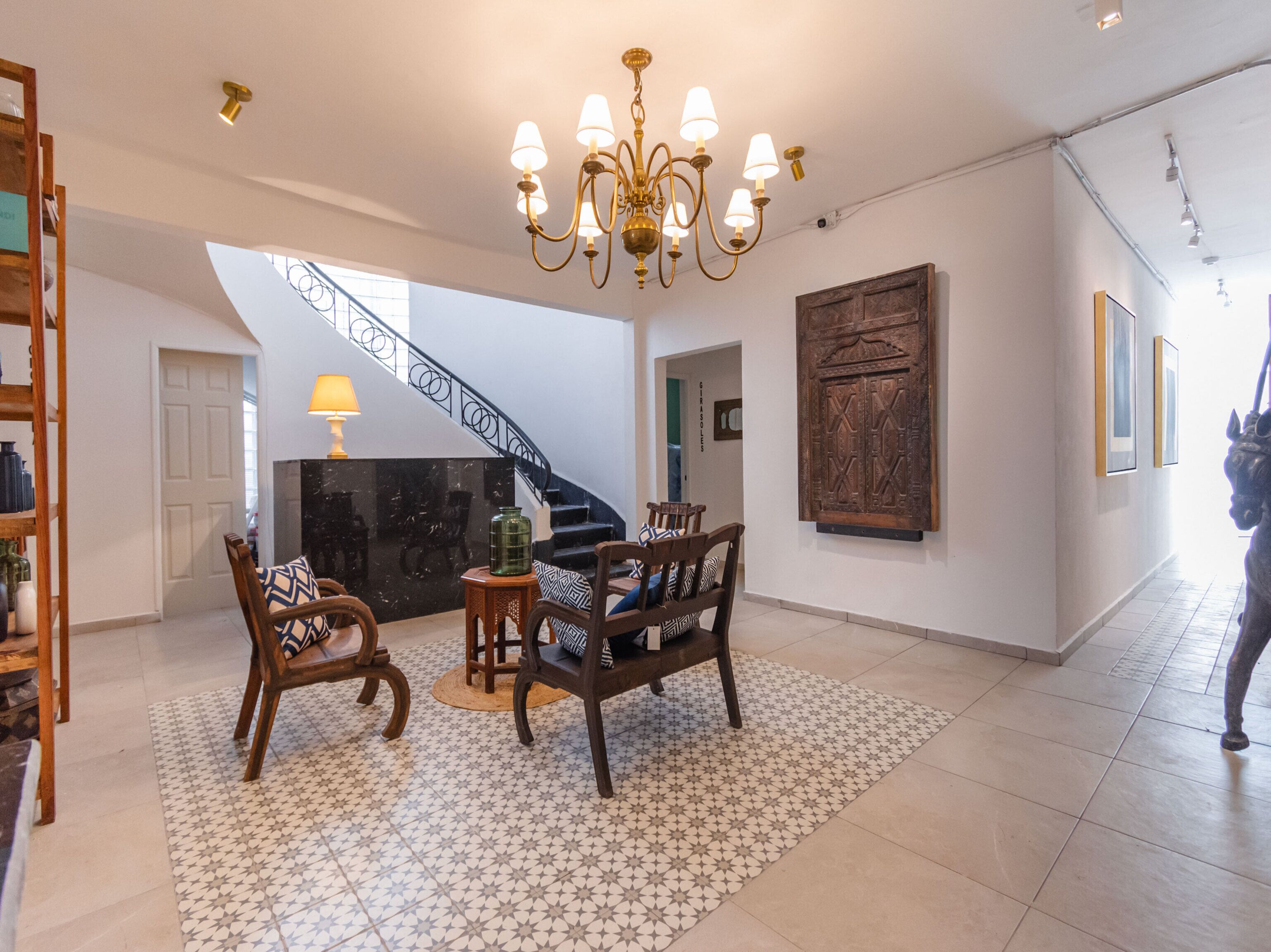 A spacious living area with a staircase, a chandelier, and a large wooden cabinet.
