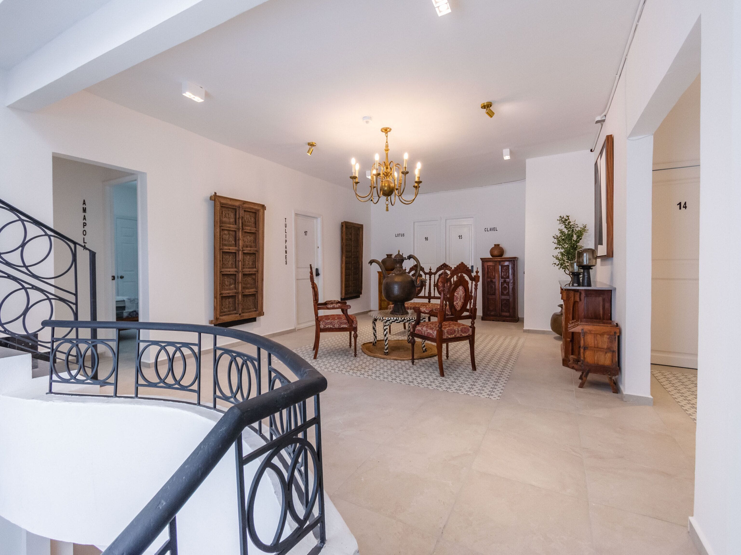 A spacious interior with a staircase, a chandelier, wooden furniture, and a tiled floor.