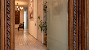 A hallway with a patterned floor, a wooden door, a potted plant, and a bench. - Collection O Lavanda Anzures Mexico City (Mexico City)