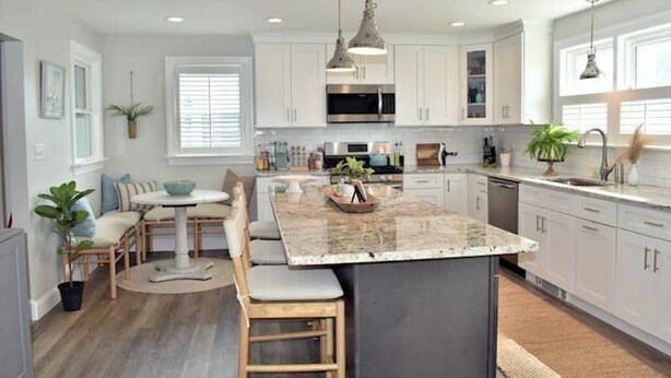 Una cocina moderna con armarios blancos, una isla central e iluminación colgante.