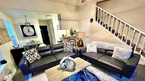 A living room with a sectional sofa, a coffee table, and a staircase.