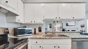 A modern kitchen with white cabinets, a stainless steel stove, a microwave, and a dishwasher.