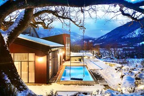 A modern building with a swimming pool, surrounded by snow-covered landscape and mountains. - La Maison Des Baronnies (La Beaume)