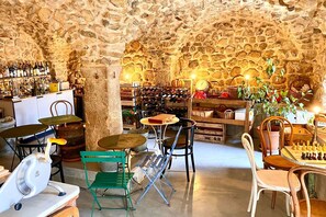 A rustic interior with stone walls, a bar area with wine bottles, and several seating options. - La Maison Des Baronnies (La Beaume)