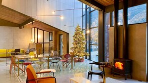 Un intérieur moderne avec un coin repas vitré, un sapin de Noël et un poêle à bois.