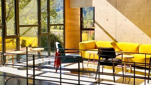 Un intérieur moderne avec de grandes fenêtres, un canapé jaune et une rambarde en verre.