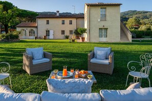 A property with a large house, outdoor seating area, and a well-maintained lawn.