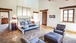 A spacious room with a bed, a chair, and a small table. There is a window with a view of the outside. - Villa Condotti - Five Bedroom Villa, Sleeps 12 (Montone)