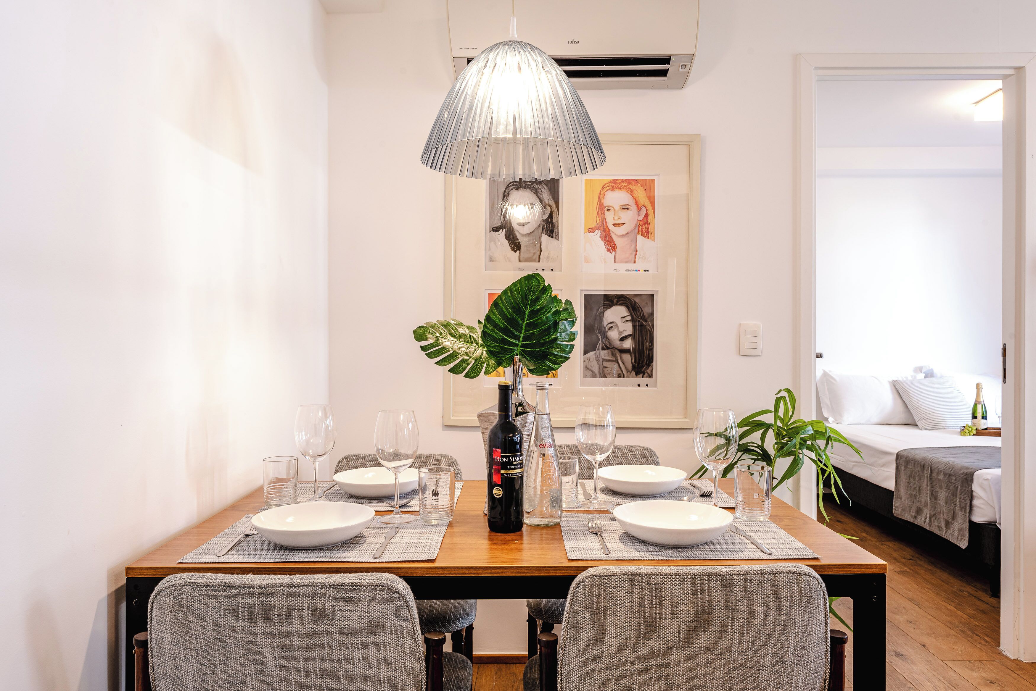 A dining table set with plates, glasses, and a bottle, surrounded by chairs.