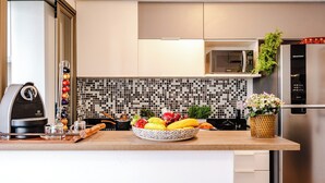 Una cocina moderna con cafetera, frutero y refrigerador.