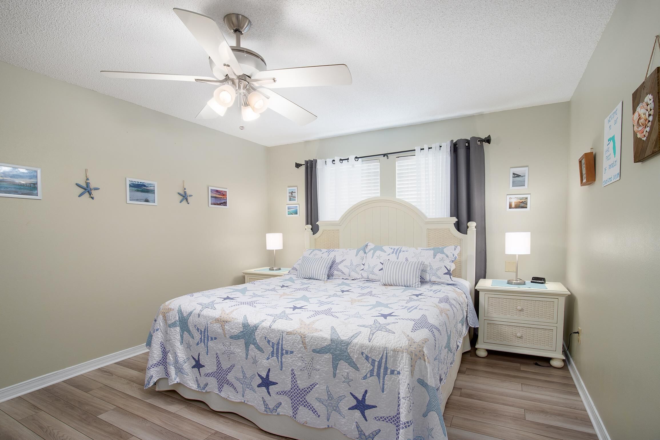 A bedroom with a bed, nightstands, a ceiling fan, and wall decorations.
