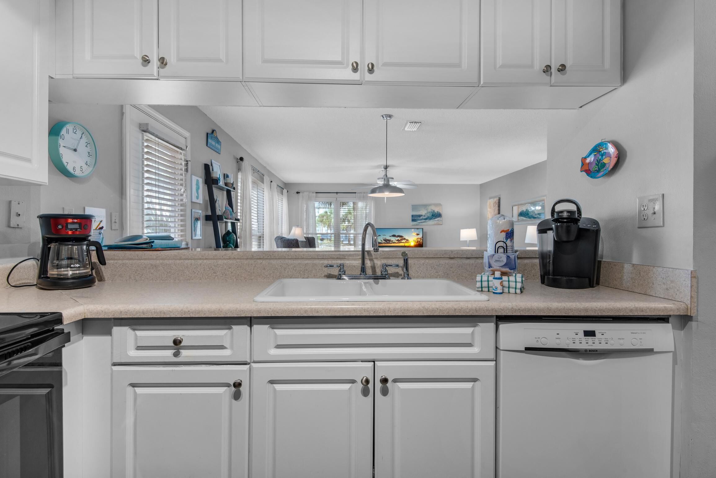 A kitchen with white cabinets, a sink, a coffee maker, and a dishwasher.