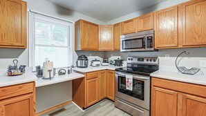 A kitchen with wooden cabinets, a microwave, a stove, and a sink.